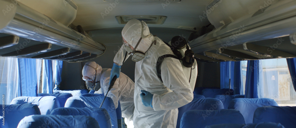 HazMat team in protective suits decontaminating public transport tourist bus interior during virus outbreak - obrazy, fototapety, plakaty 
