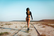 © ClaudiK - Full length image of Sexy fashion female biker girl in black helmet in dessert. Young beautiful model in black crop top and bikini suit walking away in desert USA. Back view, horizontal, copy space.
