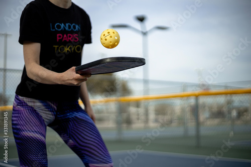 Woman playing pickleball match with whiffle ball and pickle ball paddle