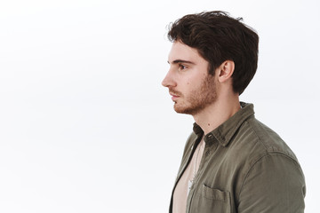 Profile portrait of ordinary caucasian guy with bristle, looking left at blank white cope space, no emotions, casual expression, standing in queue, waiting for someone, people and promo concept