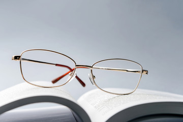 Composition with reading glasses taken close-up on the pages of an open book