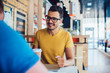 © BullRun - Cheerful young man talking with friend in cafe
