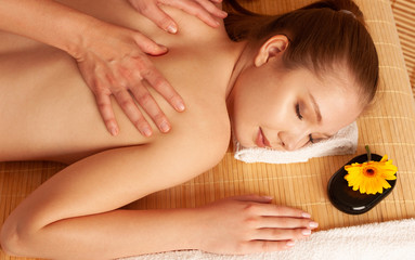 Beautiful young woman having a massage treatment in spa salon - wellness