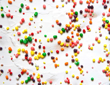 Rainbow Colored Candy Sprinkled On A White Background