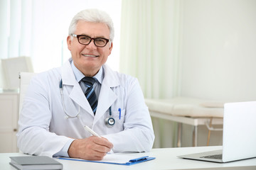 Wall Mural - Portrait of senior doctor in white coat at workplace