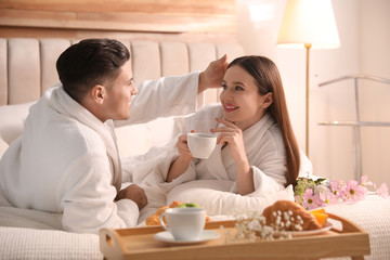 Canvas Print - Happy couple in bathrobes having breakfast on bed at home