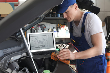 Poster - Mechanic with laptop doing car diagnostic at automobile repair shop