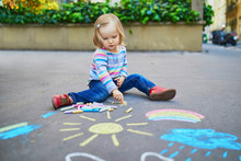 Adorable Toddler Girl Drawing With Colorful Chalks On Asphalt