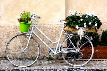 Wall Mural - Finalborgo (SV), Italy - December 12, 2017: A white bicycle whith flowers in Finalborgo village, Finale Ligure, Liguria, Italy