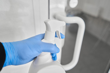 Disinfection, cleaning and washing of door handles. COVID-19. Prevention of coronavirus infection. closeup of a disinfecting the door handle by spraying a sanitizer from a white bottle