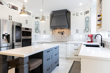 Beautiful Contemporary Style Kitchen with White Cabinets and a gray island with matching canopy range hood, white quartz countertops and stainless steel appliances