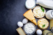 Fresh dairy products, milk, cottage cheese, eggs, yogurt, sour cream and butter on black background, top view