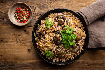 Poster - Buckwheat porridge with mushrooms in the frying pan on wooden table, top view