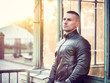 © theartofphoto - One handsome young man in urban setting in European city, standing, wearing black leather jacket and jeans at sunset