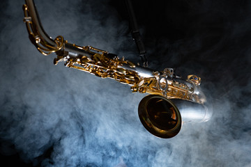 Golden shiny alto saxophone on black background with smoke. copy space