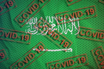 Saudi Arabia flag and many red Covid-19 stamps. Coronavirus or 2019-nCov virus concept