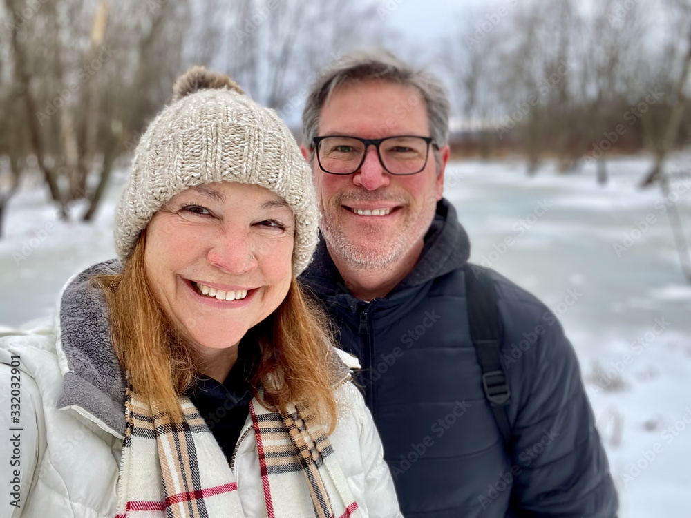 Happy middle aged couple taking a selfie outdoors in winter - obrazy, fototapety, plakaty 
