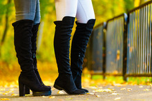 Two women wearing black knee high boots