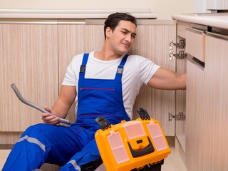 Young repairman working at the kitchen