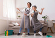 Couple Having Fun While Cleaning Home, Playing With Mop And Broom
