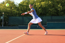 Professional Equipped Female Tennis Player Beating Hard The Tennis Ball With Racquet.
