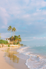 Wall Mural - Tropical beach at sunset time. Palm trees and sandy sea shore with soft ocean waves. Ahangama, Sri Lanka.