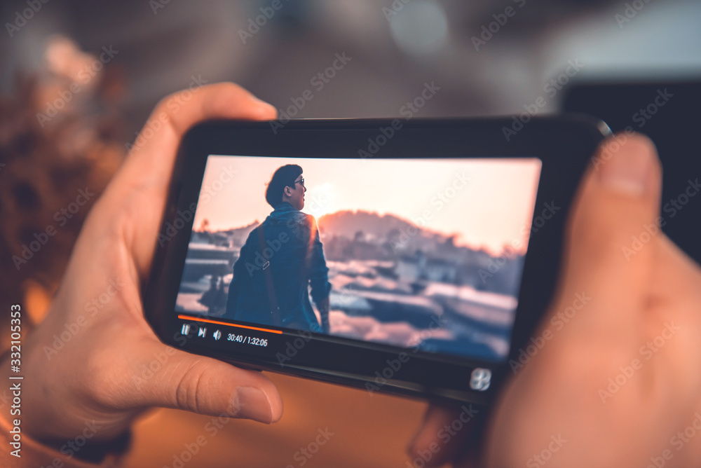 человек смотрит на экран смартфона с приложением кинотеатра