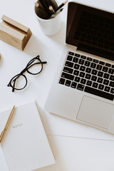 Wall Mural - Home office desk workspace with laptop, notebook, glasses on white table. Flat lay, top view. Women's, girl boss work or business background.