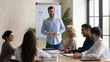 © fizkes - Smiling male coach joke make whiteboard presentation for multiracial businesspeople at briefing, happy diverse colleagues have fun laugh discussing business ideas brainstorming at team meeting