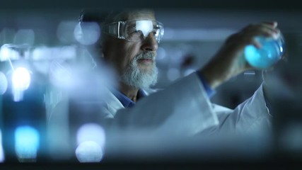 Wall Mural - Senior male researcher carrying out scientific experiment in a lab. Checking results on a tablet.