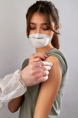 Doctor just vaccinated a girl and giving her cotton wool. Medicine and health care concept. Grey isolated background.