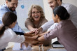 © fizkes - Excited diverse colleagues stack hands in pile motivated for shared victory or win, overjoyed multiracial businesspeople engaged in teambuilding activity at office meeting together, teamwork concept