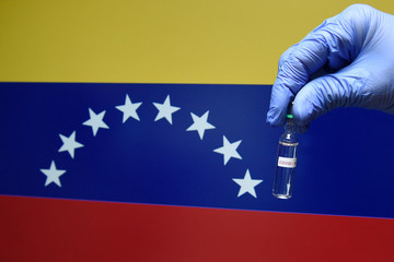 Wall Mural - Corona virus or Covid-19 in Venezuela   , sample blood tube in hand with Venezuela flag on background