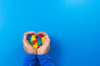 © vejaa - World autism awareness day concept. Child hands holding colorful puzzle heart on blue background