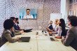 © Mediteraneo - Team of business people looking doctor speech at projector screen in video conference