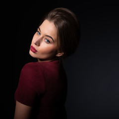 Leinwandbilder - Portrait of attractive young woman over black background. Amazing girl with perfect makeup wearing elegant deep red dress. Beauty and fashion