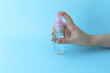 © Tatyana - Pink bottle with antibacterial spray in hand on a blue background. Antiseptic for hand and surface treatment. Selective focus. Prevention of coronavirus