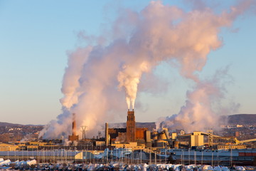 Beautiful golden hour winter view of boats in marina and fuming factory chimneys in industrial sector of Quebec City’s lower town, Quebec, Canada