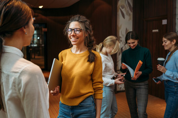 Group of happy business woman have meeting at modern office. Two positive female employees standing at open space and discuss working moment