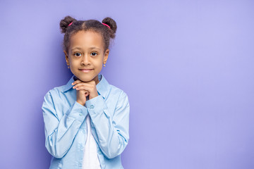 portrait of cute or african kid girl isolated over purple background. beautiful shy little girl posi