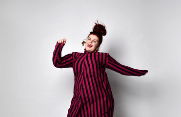 Wall Mural - Fatty ginger girl in striped dress, earrings. She is smiling, dancing and having fun while posing isolated on white background