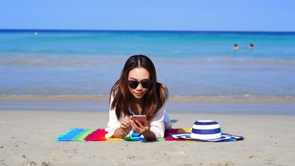 Wall Mural - Young asian woman traveler using her smartphone at tropical sand beach, Summer vacation concept