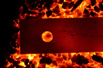 Poster -  An iron bar with a round hole is heated on a burning coal anthracite.