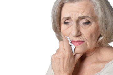 Poster - Portrait of sick senior woman in white blouse with handkerchief on white background