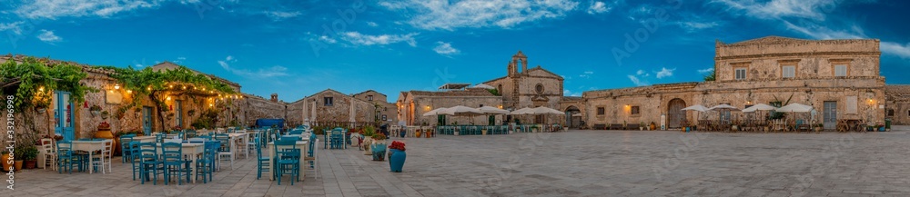 Panoramic view of the picturesque sicilian village Marzamemi, view of the traditional outdoor cafe and the church and the central square, province of Syracuse, Sicily, southern Italy - obrazy, fototapety, plakaty 