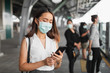 © Nattakorn - Coronavirus(Covid-19) concept, Asian woman wearing protective face mask to protect infection from coronavirus covid-19 standing at sky train and crowd people
