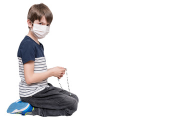 Little boy with face mask praying and holding rosary, isolated on white background