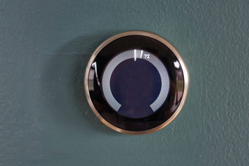 Smart home thermostat or nest with no center information isolated on a blue wall