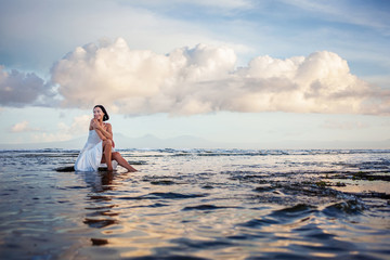 Wall Mural - Beautiful woman by the ocean at sunset