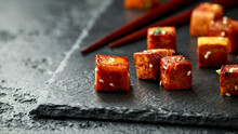 Fried Tofu With Chopstick And Sesame Seeds On Rustic Stone Board